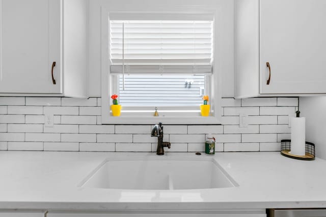 kitchen featuring backsplash, a sink, and white cabinets