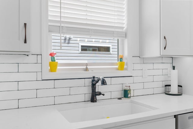 kitchen featuring a wealth of natural light, light countertops, a sink, and white cabinetry