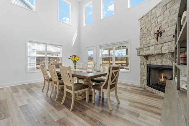 dining space featuring a stone fireplace, wood finished floors, and a wealth of natural light