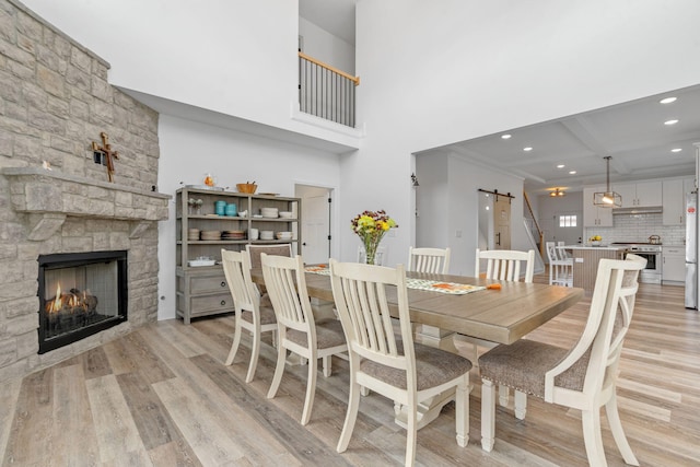 dining space featuring recessed lighting, a fireplace, light wood-style flooring, and a barn door