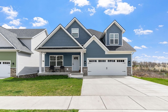 craftsman house with covered porch, a garage, driveway, stone siding, and a front yard