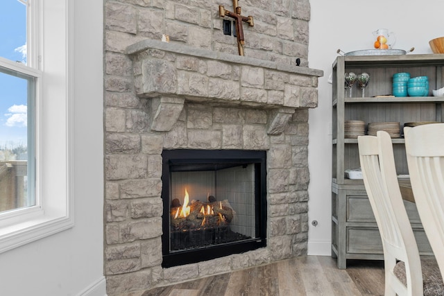 details with a warm lit fireplace and wood finished floors