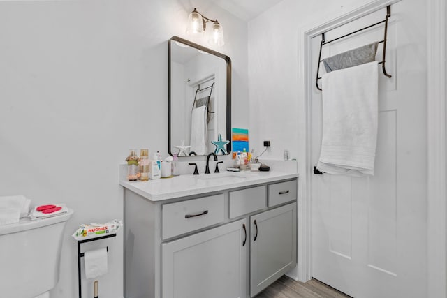 bathroom with wood finished floors, vanity, and toilet