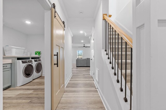 washroom with washer and dryer, crown molding, light wood finished floors, and a barn door