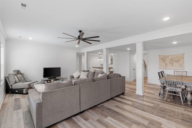 living room with light wood-style floors, ornamental molding, ceiling fan, ornate columns, and stairs