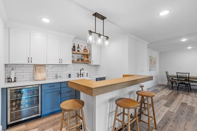 bar with beverage cooler, ornamental molding, backsplash, wet bar, and light wood finished floors