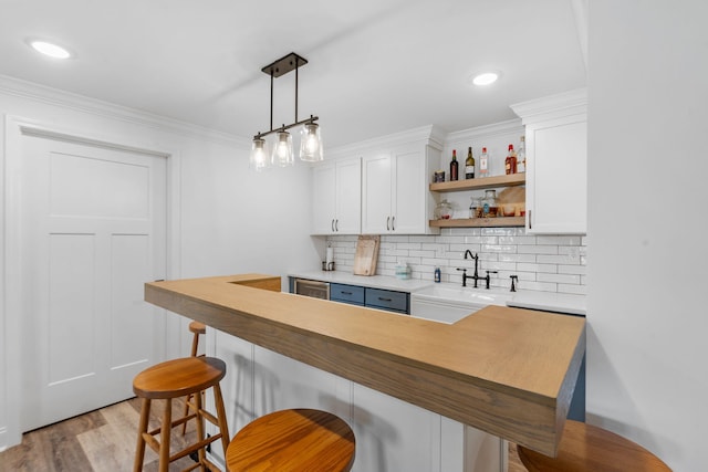 kitchen featuring decorative backsplash, white cabinets, a sink, and a kitchen breakfast bar