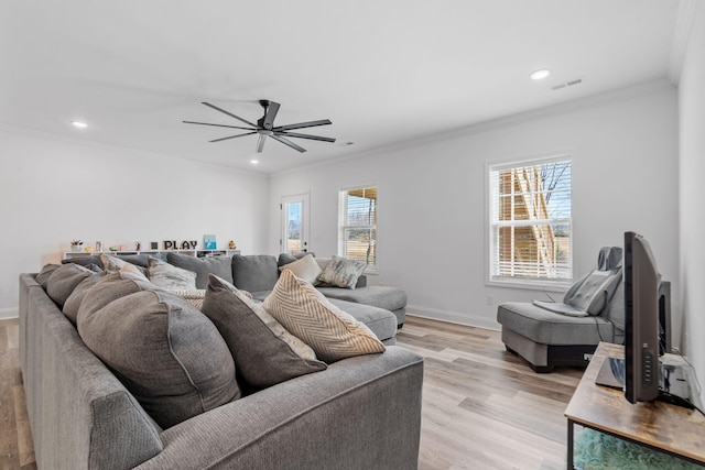 living area with baseboards, visible vents, ceiling fan, ornamental molding, and light wood-style floors