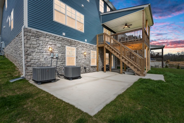 back of house at dusk featuring stairs, a lawn, cooling unit, and a ceiling fan