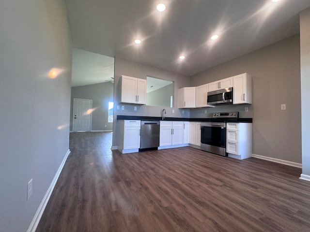 kitchen with lofted ceiling, stainless steel appliances, sink, white cabinets, and dark hardwood / wood-style flooring