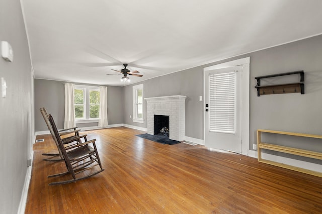 living room with a fireplace, ceiling fan, and wood-type flooring