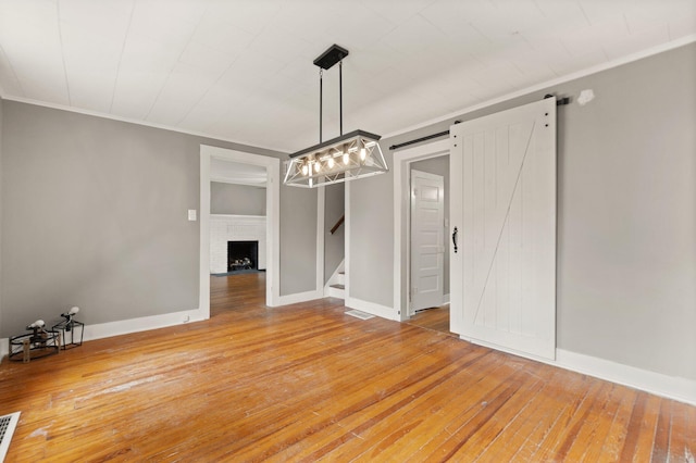 unfurnished dining area with a brick fireplace, wood-type flooring, and a barn door