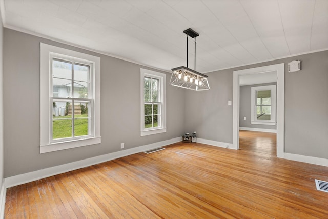 unfurnished dining area with a notable chandelier, light hardwood / wood-style flooring, and ornamental molding