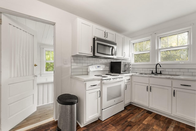 kitchen featuring dark hardwood / wood-style floors, sink, white electric range oven, a wealth of natural light, and white cabinets