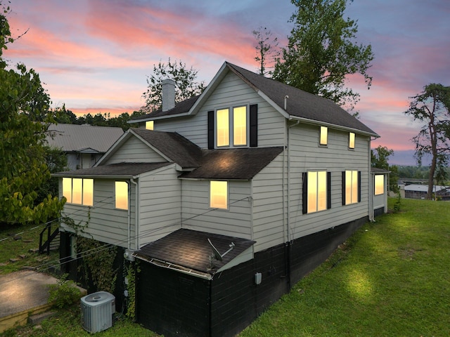 property exterior at dusk with central air condition unit and a lawn