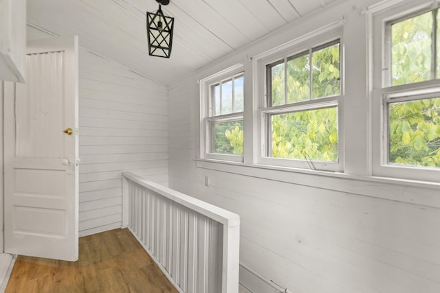 corridor with vaulted ceiling and hardwood / wood-style flooring