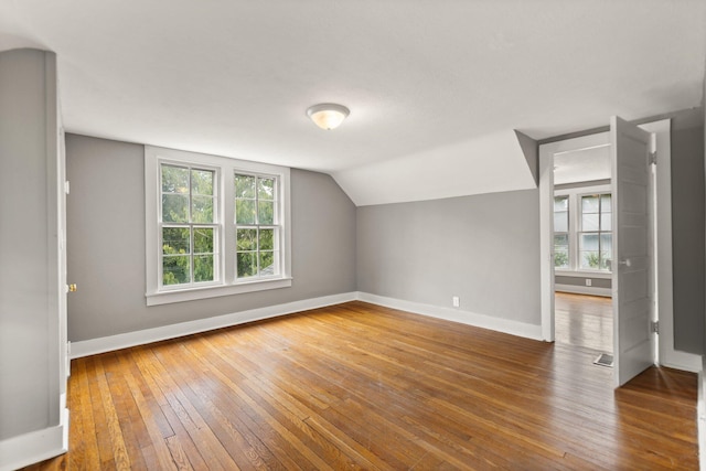 additional living space featuring plenty of natural light, lofted ceiling, and hardwood / wood-style floors