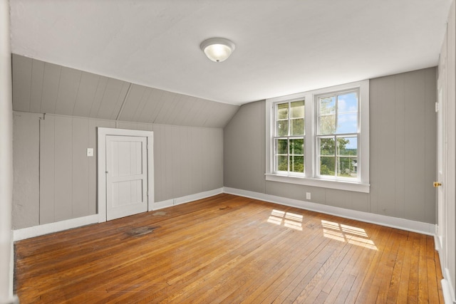 bonus room with light wood-type flooring and vaulted ceiling