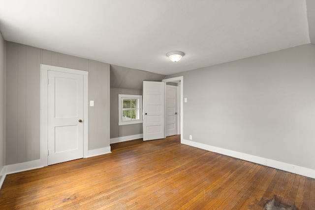 unfurnished room featuring vaulted ceiling and hardwood / wood-style flooring