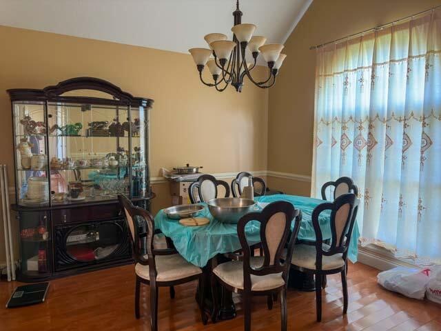 dining room featuring a notable chandelier, wood-type flooring, and vaulted ceiling