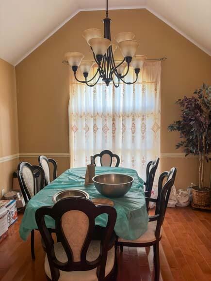 dining area with a notable chandelier, wood-type flooring, and vaulted ceiling