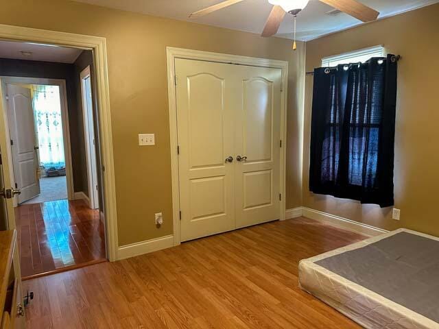 unfurnished bedroom with ceiling fan, light hardwood / wood-style flooring, and a closet