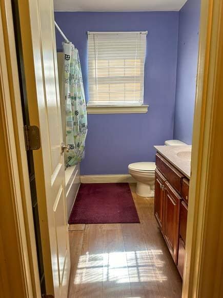 full bathroom with hardwood / wood-style flooring, vanity, toilet, and shower / bath combination with curtain