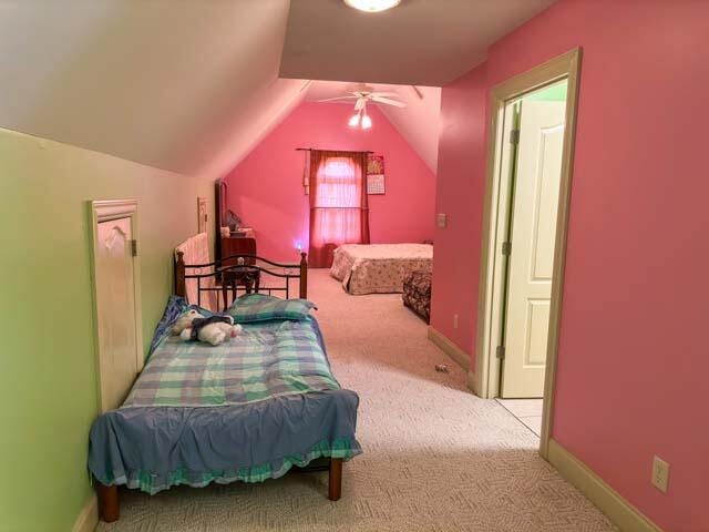 carpeted bedroom with ceiling fan and vaulted ceiling