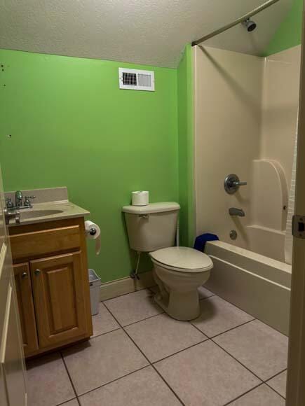 full bathroom with shower / bath combination, vanity, tile patterned flooring, and toilet