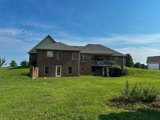 rear view of property with a balcony and a yard