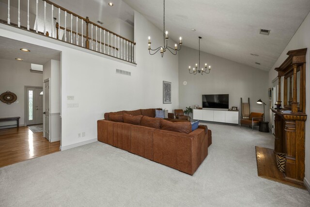 living room with high vaulted ceiling, an inviting chandelier, and hardwood / wood-style floors