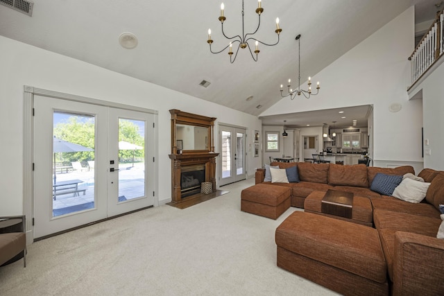 carpeted living area featuring high vaulted ceiling, french doors, visible vents, and an inviting chandelier