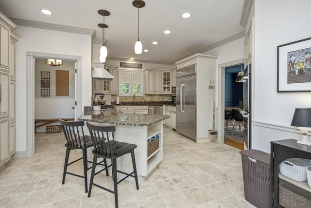 kitchen with dark stone counters, ornamental molding, light tile patterned floors, built in appliances, and hanging light fixtures