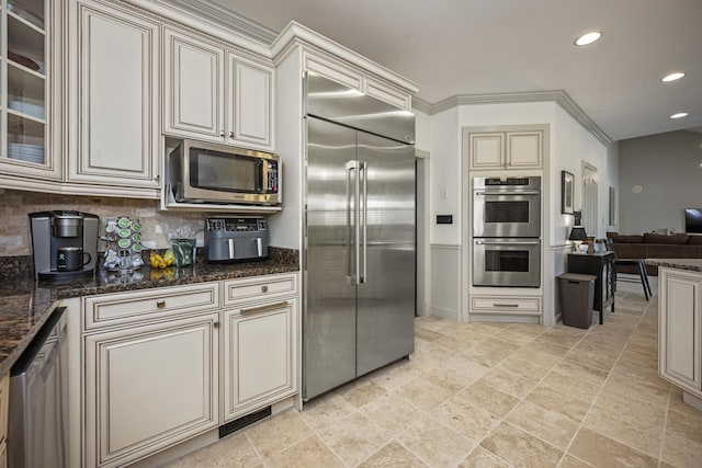 kitchen with recessed lighting, open floor plan, appliances with stainless steel finishes, cream cabinetry, and decorative backsplash