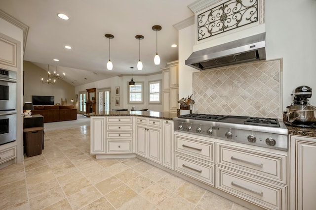 kitchen with dark stone counters, tasteful backsplash, cream cabinetry, stainless steel appliances, and wall chimney range hood