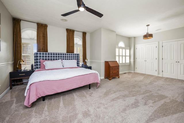 bedroom with a ceiling fan, carpet flooring, baseboards, and two closets