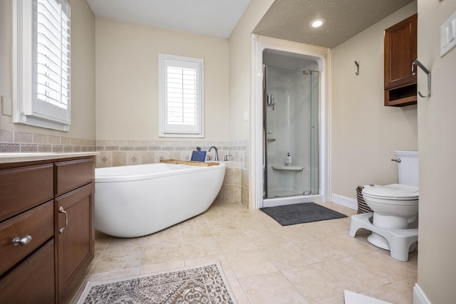 full bath featuring a stall shower, a freestanding tub, toilet, and tile patterned floors