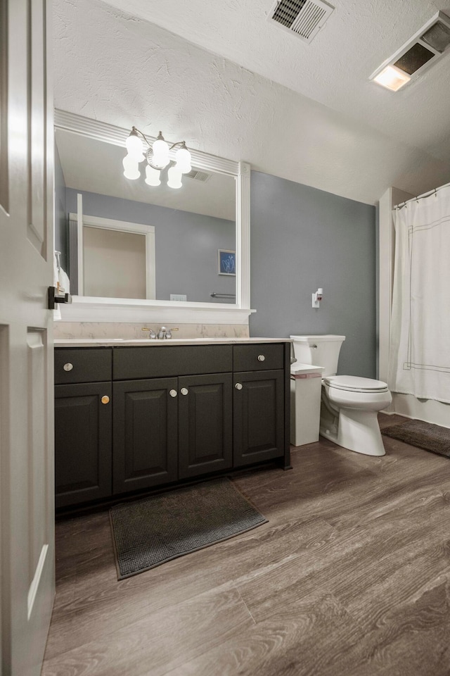 bathroom featuring hardwood / wood-style flooring, a textured ceiling, vanity, curtained shower, and toilet