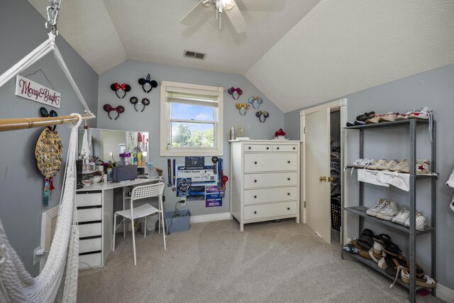 carpeted home office with a textured ceiling, ceiling fan, and vaulted ceiling