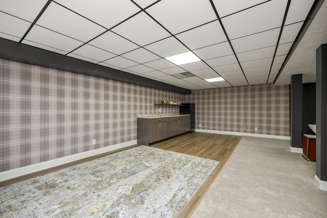 bar with wood finished floors, a drop ceiling, baseboards, and wallpapered walls