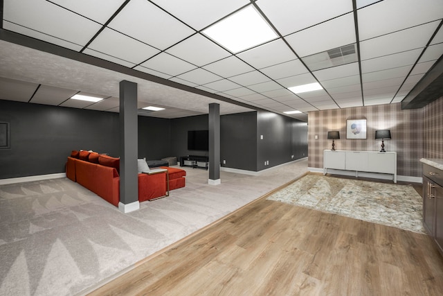 basement featuring a paneled ceiling and light carpet