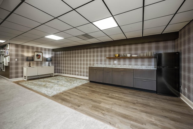 bar featuring wallpapered walls, baseboards, a paneled ceiling, freestanding refrigerator, and light wood-type flooring