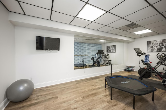 exercise area with wood finished floors, a paneled ceiling, and baseboards