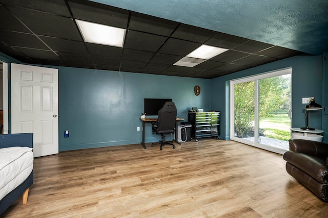 home office with wood-type flooring and a paneled ceiling