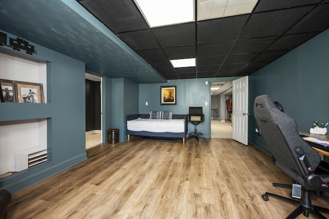 bedroom with a drop ceiling, wood finished floors, and baseboards