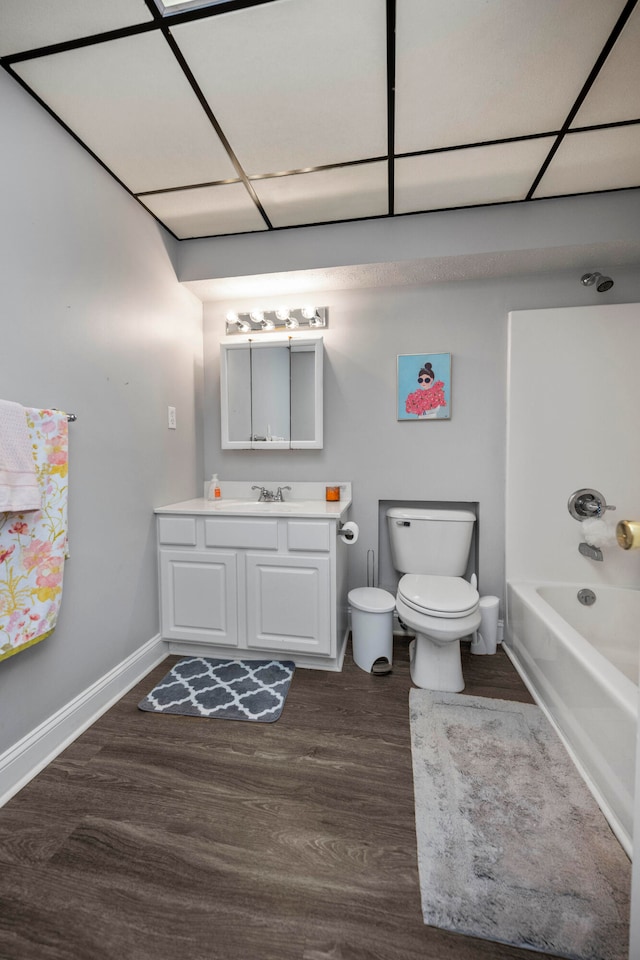 full bathroom featuring toilet, hardwood / wood-style flooring, washtub / shower combination, and vanity