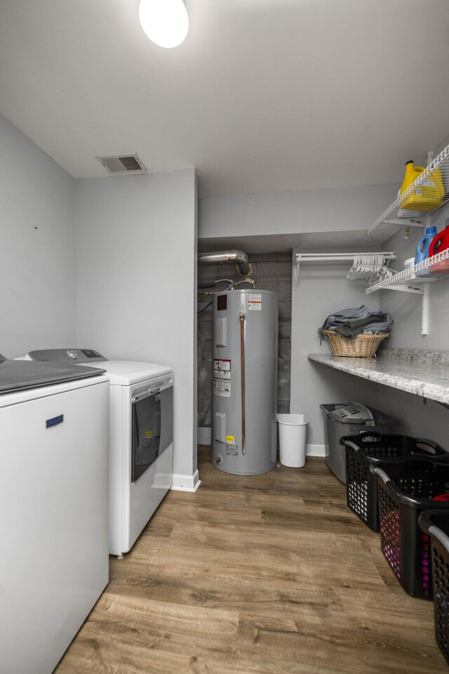 washroom featuring washer and dryer, water heater, and light hardwood / wood-style flooring