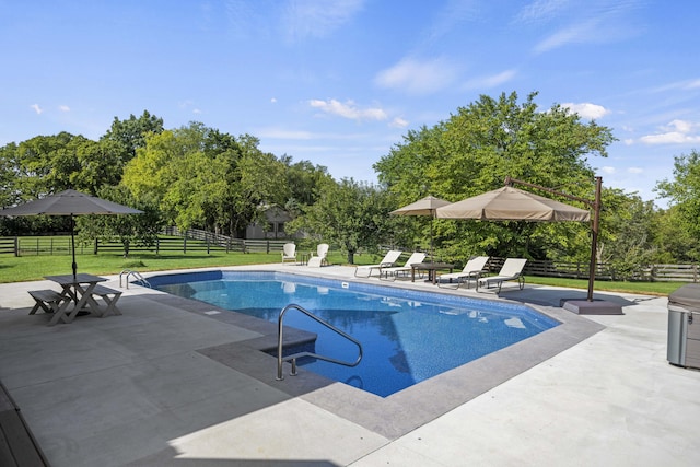 pool featuring a patio area, fence, and a yard