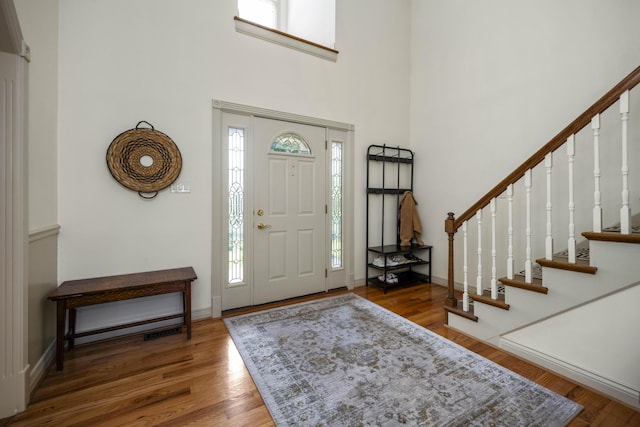 foyer entrance with baseboards, stairs, a high ceiling, and wood finished floors