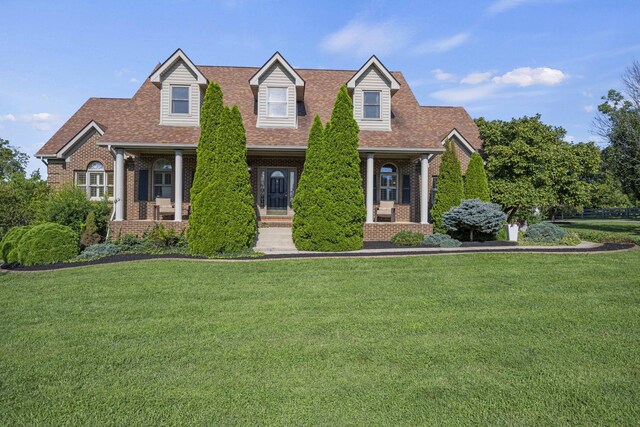 new england style home with a front yard and covered porch